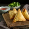 Indian samosas with sauce and herbs.