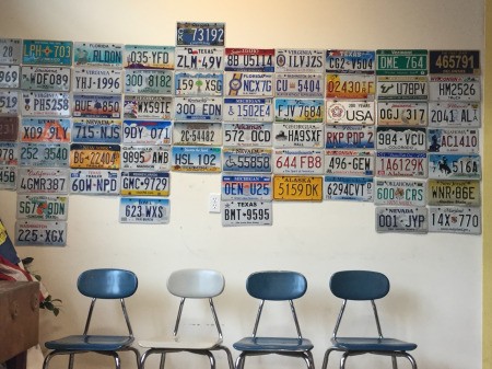 A collection of license plates on a wall at the DMV.