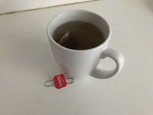 A cup of tea with a paper clip attached to the tea bag tab.