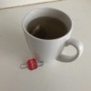 A cup of tea with a paper clip attached to the tea bag tab.