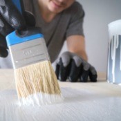 A man painting a wooden board with a paintbrush.