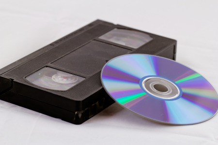 A VHS tape next to a DVD disk.