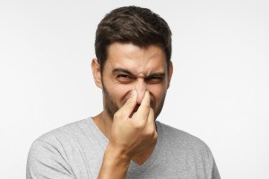 A man holding his nose from a bad smell.