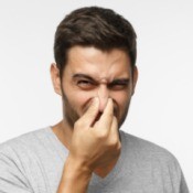 A man holding his nose from a bad smell.