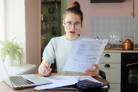 A shocked woman reviewing a utility bill.