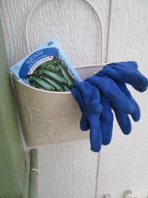 Bucket Garden Storage - newly painted pail on side of garden shed with seed packet and garden gloves inside