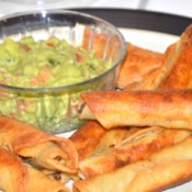 A plate of fried beef taquitos served with guacamole.