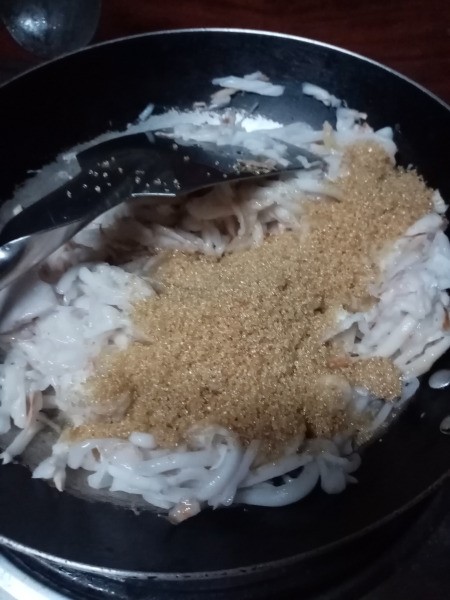 sugar added to coconut meat in pan