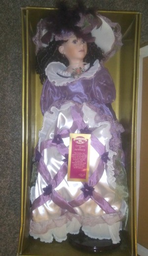 Value of a Collectible Memories Porcelain Doll - doll in box wearing a satin dress with purple ribbon trim