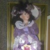 Value of a Collectible Memories Porcelain Doll - doll in box wearing a satin dress with purple ribbon trim