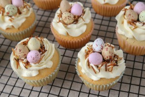 Cupcakes decorated with colorful candy eggs and toasted coconut.