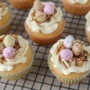 Cupcakes decorated with colorful candy eggs and toasted coconut.