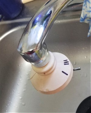 A faucet with a multifunction sprayer on the end, with markings in Sharpie.