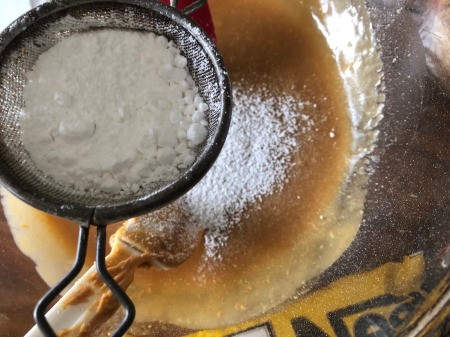 sifting powdered sugar into bowl