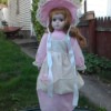 Identifying a Heritage Porcelain Doll - doll wearing a long pink dress with white apron and matching hat