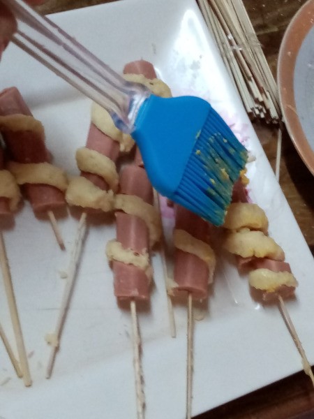 brushing Sausage Twisters with butter