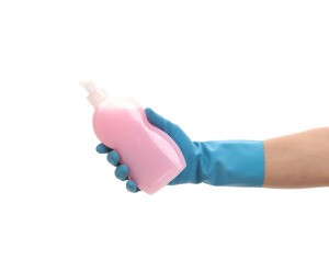 Hand in a rubber glove holding pink dish soap.