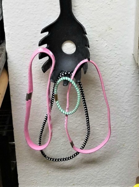 Hair ties hanging from the tines of a spaghetti spoon.