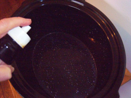 spraying crock pot with oil
