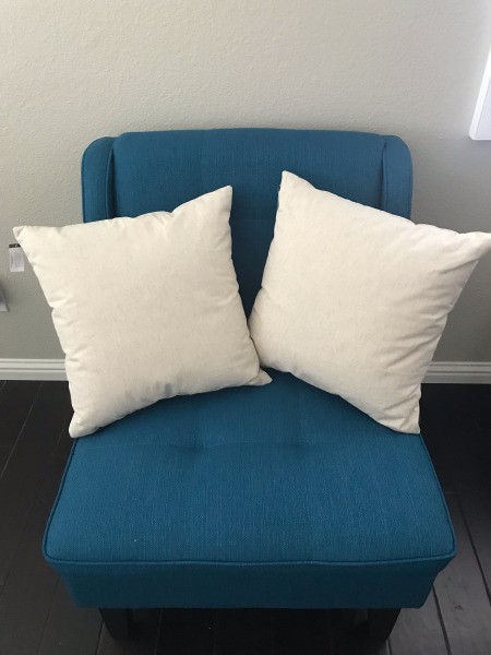 Two white pillows on a blue chair.