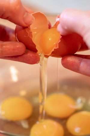 Eggs being cracked into a bowl.