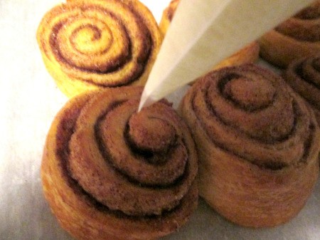 squeezing icing on rolls