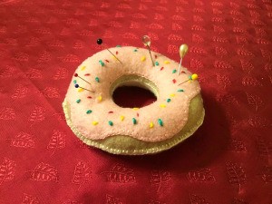 Donut Pin Cushion - pink frosted donut pincushion on red background