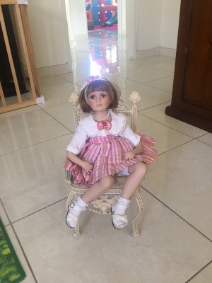 Identifying a Porcelain Doll - doll sitting on a wicker style chair