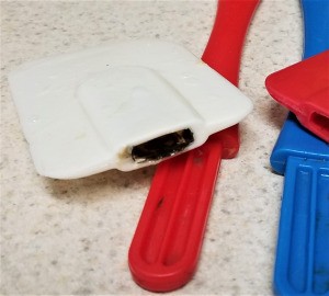A close up of a dirty spatula with the handle removed.