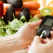 Someone checking their insulin levels next to healthy produce.