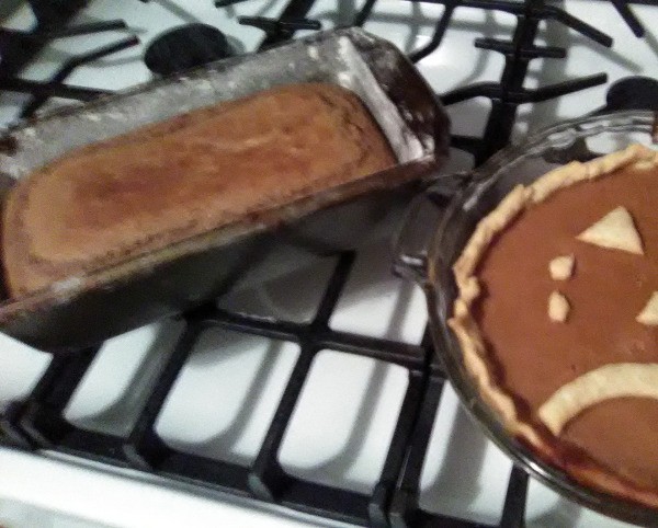 A loaf of quick bread next to a pumpkin pie.