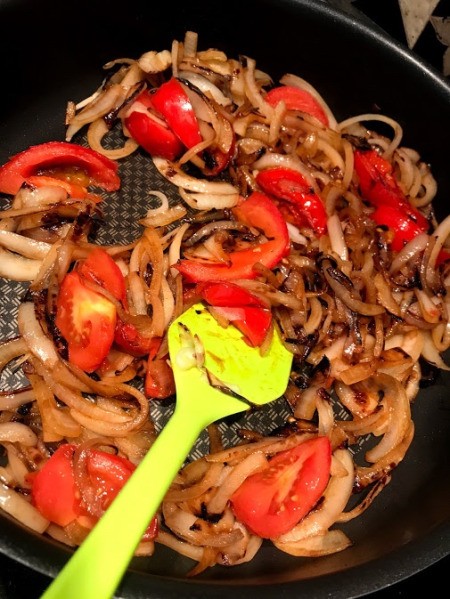 adding tomatoes to onions in pan