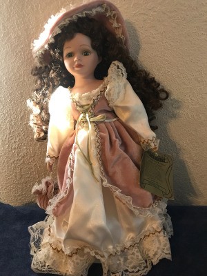 Value of a Seymour Mann Connoisseur Collection Doll - doll wearing a long ivory dress with a rose over skirt and hat