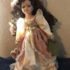 Value of a Seymour Mann Connoisseur Collection Doll - doll wearing a long ivory dress with a rose over skirt and hat