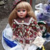 Selling Porcelain Dolls - doll wearing a print dress and matching green and red plaid hat