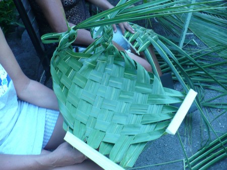 Weaving Coconut Leaf Plates - finished plate in foreground and someone making another in the background