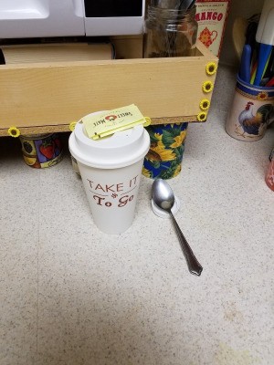 A plastic lid being used as a small spoon rest for coffee.