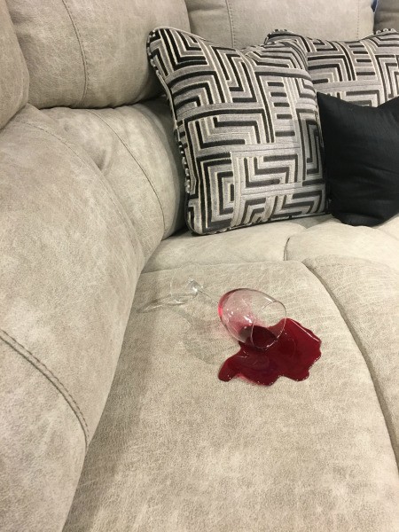 A glass of wine spilled on a upholstered fabric couch.
