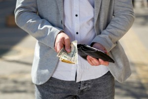 A man holding out money from his wallet.