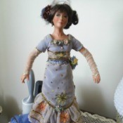 Value of a Kathleen Hill Porcelain Doll - doll wearing a long blue dress with ruffled bottom over a dark blue underskirt