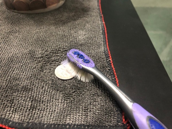 Scrubbing coins with a toothbrush.