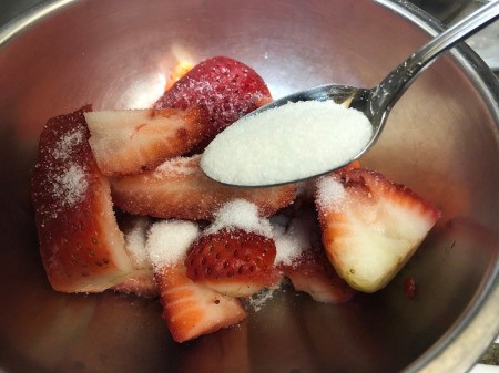 adding sugar to strawberry slices