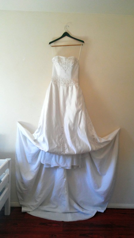 A wedding dress hanging on a wall.