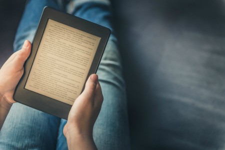 A person reading a Kindle in their lap.