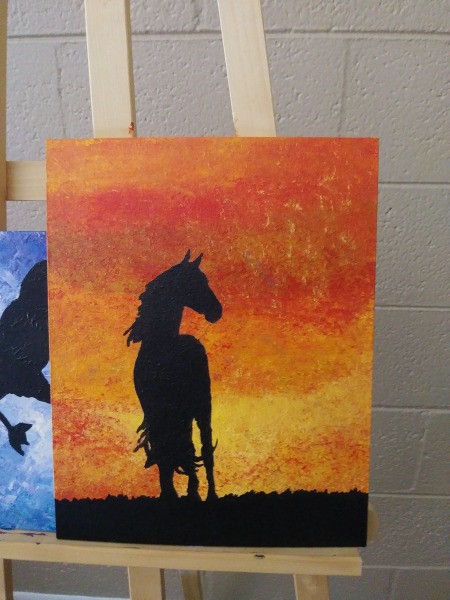 A horse silhouette on a sunset colored background.