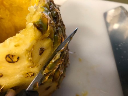 cutting skin off pineapple