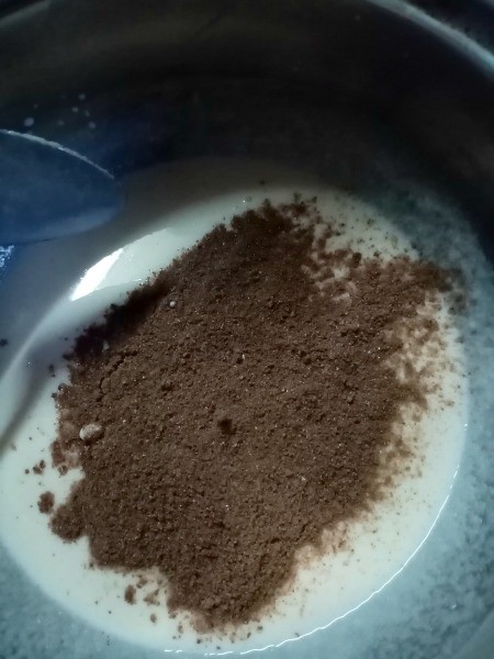 adding chocolate powder to milk