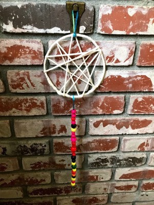 Dreamcatcher with Wooden Beads - dream catcher hanging against a brick wall