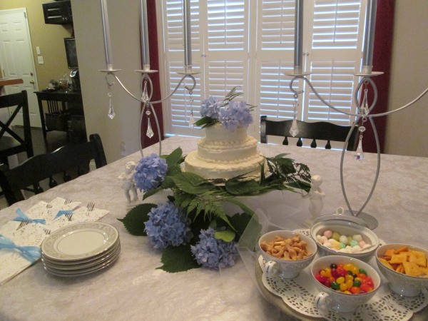 A decorated table with a wedding cake, china and some small dishes of snacks and candy.