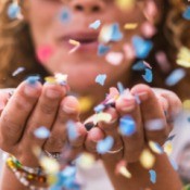 A woman blowing confetti at the camera.